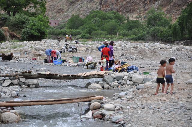 Mulheres lavando roupa no rio, e crianças brincando na água