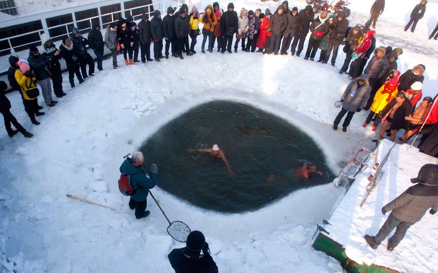 Buracos são feitos no rio congelado para o mergulho dos nadadores (Foto: reprodução)