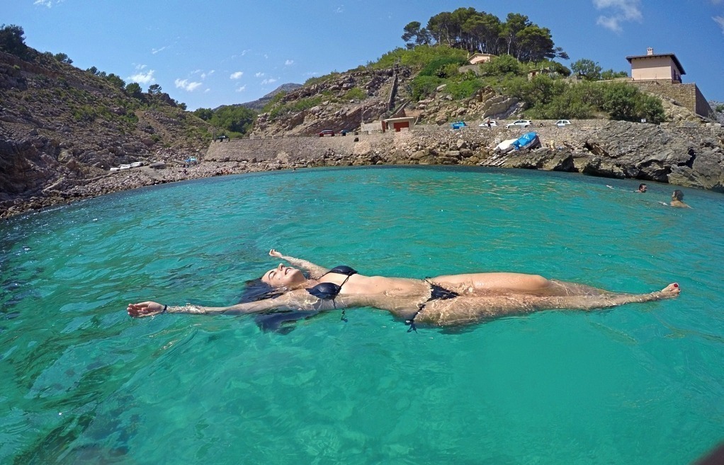 Mulher boiando no mar azul turquesa de Mallorca