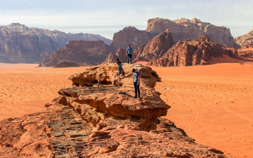 Pessoas em cima de pedra para admirar o cenário do deserto. 