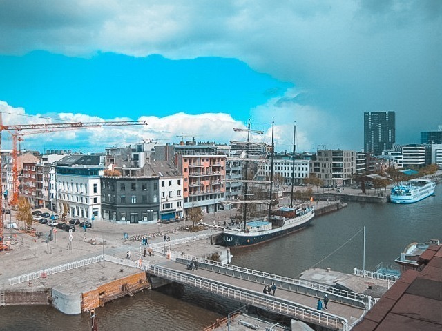 Vista do museu MAS na Antuérpia, com prédios baixos e um rio que é cortado por uma ponte.