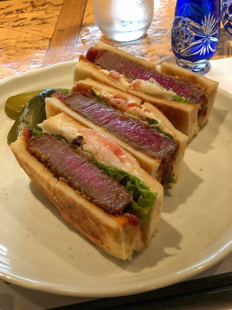 Três pedaços de sanduíche com um grosso filé de carne de wagyu dentro de cada um.