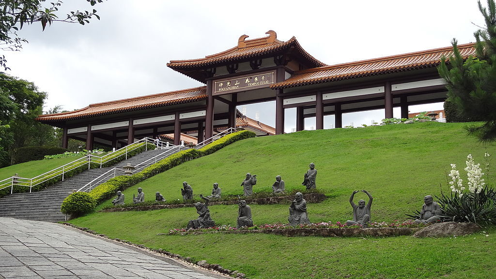 Entrada do Templo Zu Lai, com escadaria, grama e estátuas na frente