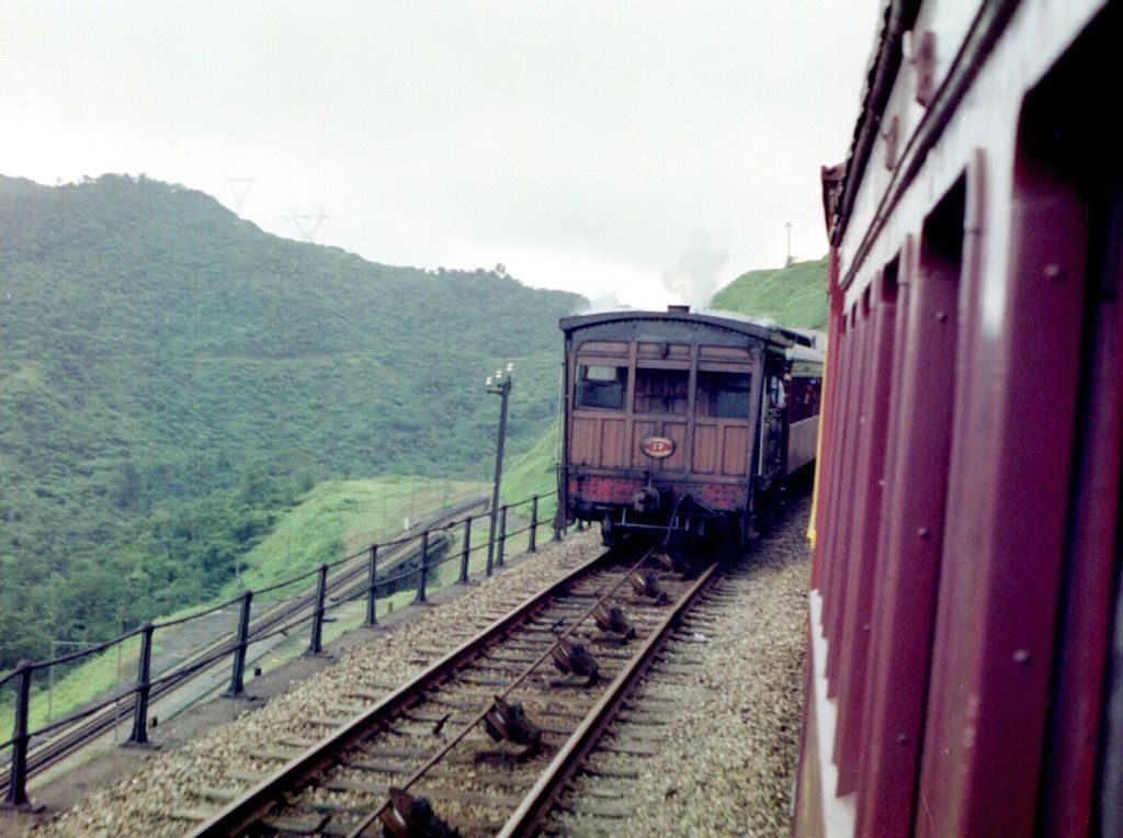 Trem passando por estrada de ferro ao lado de um penhasco