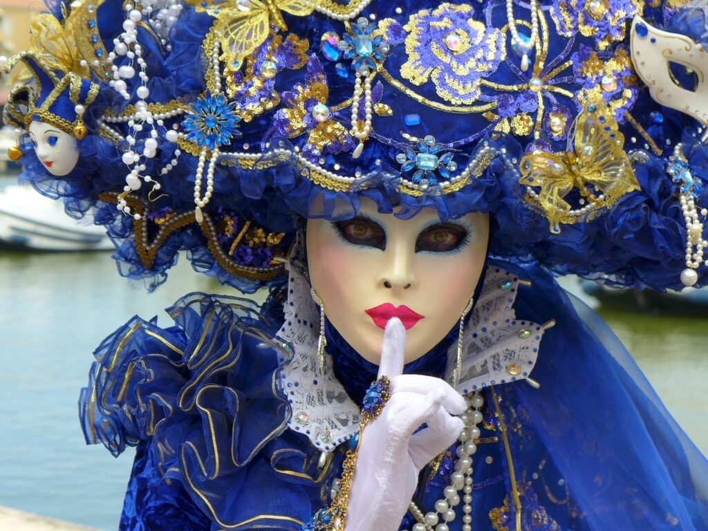 Pessoa usando máscara de carnaval de Veneza fazendo sinal de silêncio com a mão