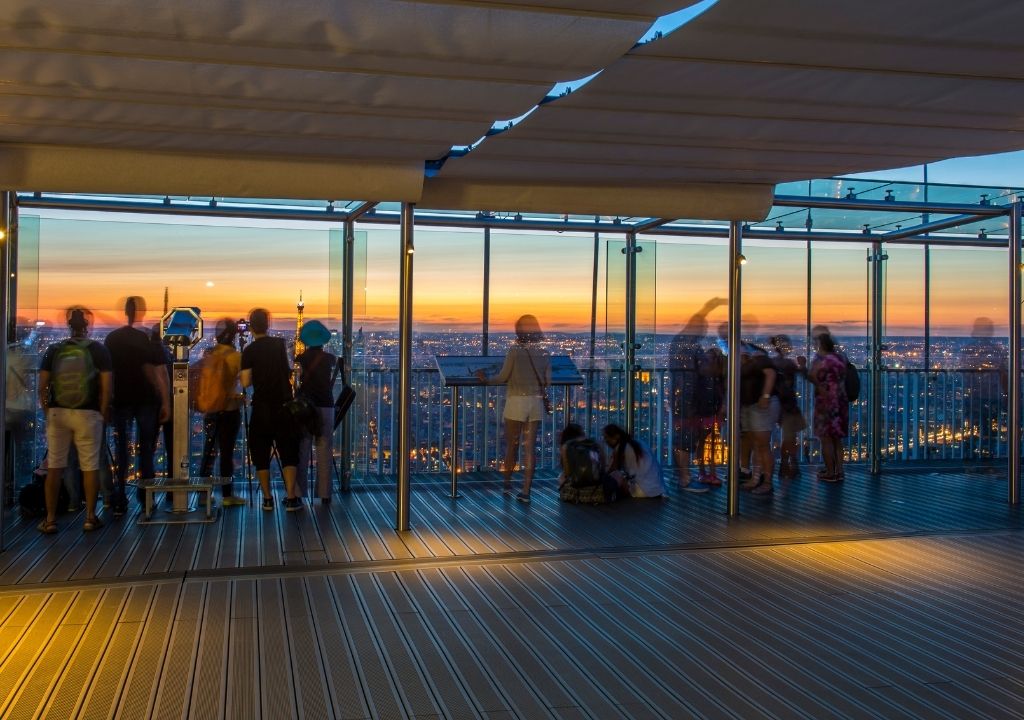 turistas curtem a vista de Paris ao entardecer no mirante da Torre Montparnasse