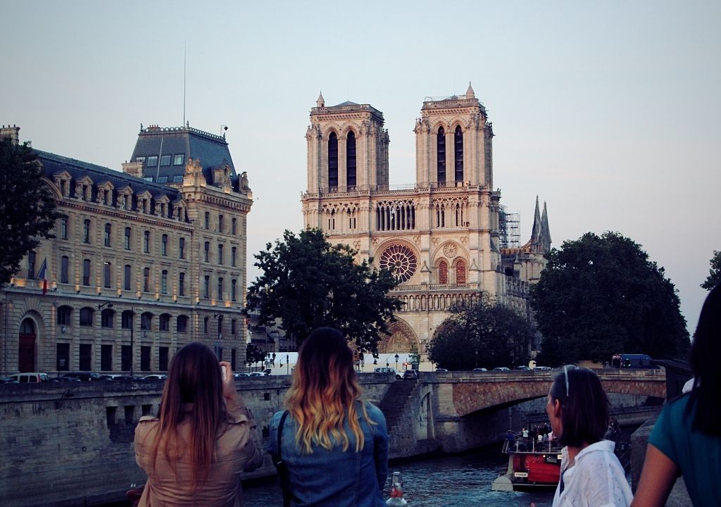 Turistas fotografam a Catedral de Notre Dame ao entardecer