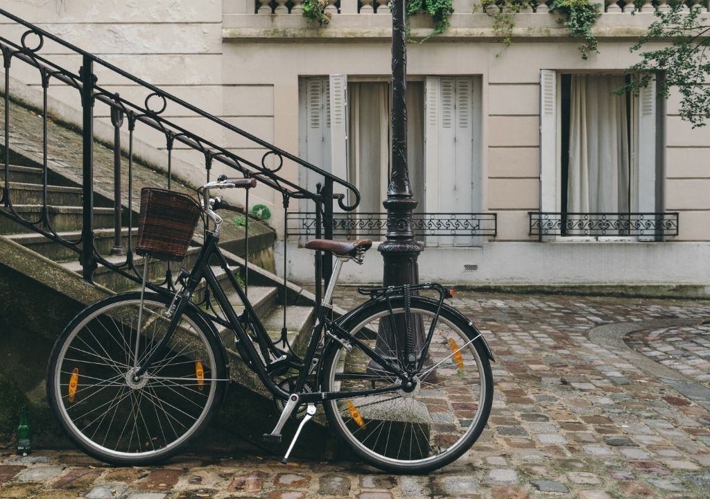 uma bicicleta em frente a uma escada e um prédio de fachada clara em Paris