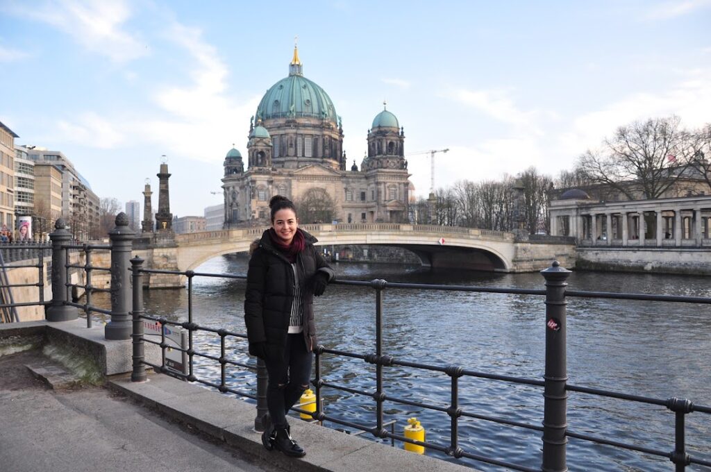 Mulher posa em frente a catedral de Berlim e do rio. 
