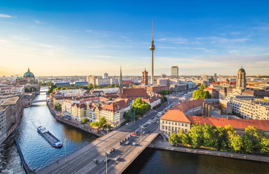 Vista aérea da cidade de Berlim, com a catedral com teto verde ao fundo, o rio Spree e a torre de tv. 